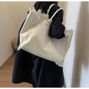 Détail d'un grand cabas en toile avec franges porté à l'épaule par un mannequin