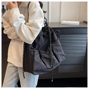 Detail of a black large-capacity nylon shoulder bag with drawstring and pleated pockets