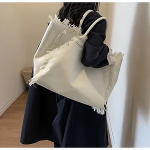 Détail du sac fourre-tout en toile blanc cassé avec bords à franges et intérieur spacieux