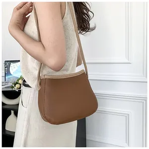 Vue détaillée du sac seau en cuir marron avec bandoulière contrastée de couleur crème