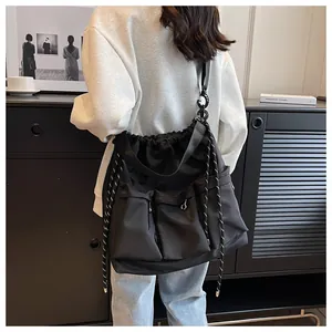 Detail of black nylon multi-pocket messenger bag with drawstring and wide strap