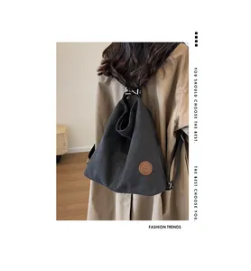 Detail of black canvas backpack showing a brown leather logo and vintage drape texture
