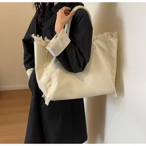 Détail du grand sac cabas en toile avec bordures à franges porté par un mannequin
