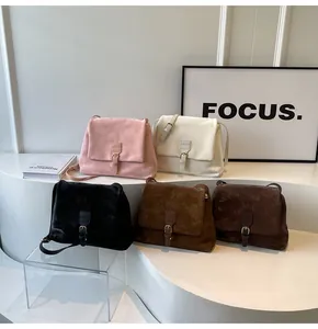 Five vintage matte suede messenger bags in various colors on a modern display stand