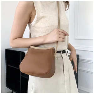 Détail du sac seau en cuir grainé marron caramel avec bordure contrastée et bandoulière