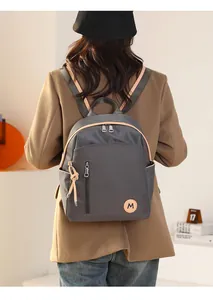Detalle de una mochila de nailon gris oscuro con toques de cuero sobre una chaqueta chic
