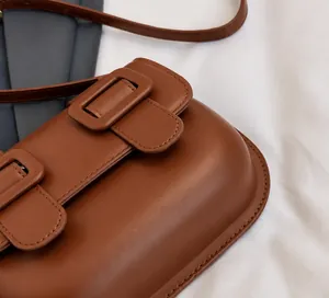 Close-up of brown PU leather crossbody bag featuring dual square decorative buckles