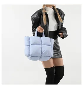 Quilted light blue puffer tote bag shown on a model with a stylish leather jacket