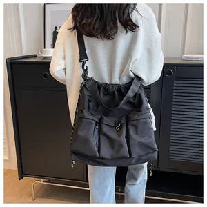 Detailed back view of a large black nylon crossbody bag featuring multiple utility pockets