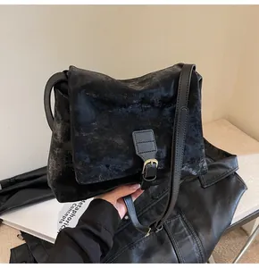 Detail of a vintage black messenger bag with adjustable strap and flap buckle closure
