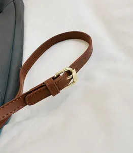 Detail of adjustable brown faux leather strap with golden metal buckle on a square bag