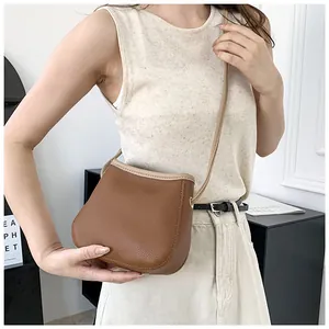 Détail du sac seau marron vintage avec texture litchi et bordure beige sur la bandoulière
