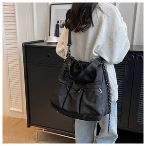 Detail of black nylon tote bag featuring three front zip pockets and drawstring closure
