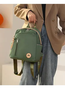 Detalle de mochila de nailon verde oscuro con ribete de cuero y cremallera metálica