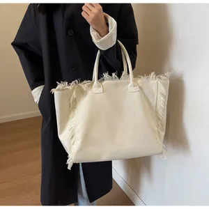 Détail du sac cabas en toile montrant des franges et des doubles poignées solides