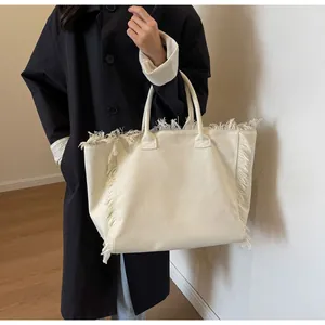 Vue détaillée d'un grand sac cabas en toile avec des franges et des anses solides