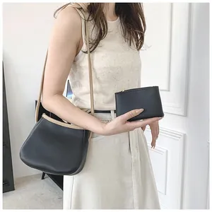 Détail du sac seau noir en cuir grainé avec lanières kaki et pochette assortie à zip doré