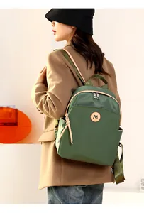 Detail of dark green waterproof oxford backpack with leather M logo and side pockets