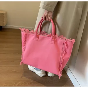 Détail d'un sac cabas en toile rose avec bords effilochés et anses minimalistes