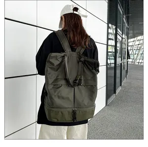 Rückansicht eines olivgrünen wasserdichten Nylon-Rucksacks, getragen vor einer weißen Wand