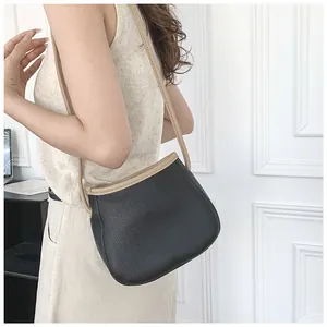 Détail du sac seau noir avec bordure beige montrant le profil et la texture du cuir