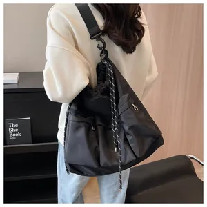 Detail view of black large capacity crossbody bag with drawstring closure and front zip pockets