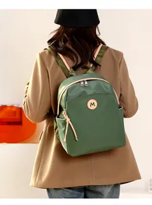 Rear view of model wearing a deep green oxford fabric backpack with light khaki zipper details