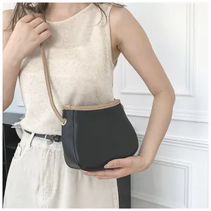 Détail du sac seau noir en cuir grainé avec bordure beige porté par un mannequin