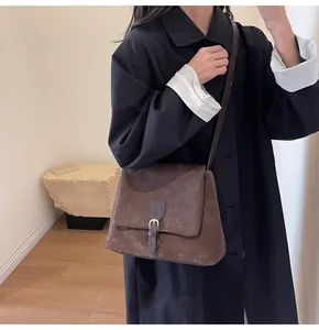 Brown vintage flap messenger bag with metallic buckle detail on a female model