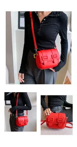 Detail showing the red leather flap bag with square ring accents and adjustable strap