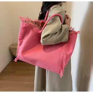 Sac fourre-tout en toile rose avec franges élégantes porté à l'épaule par un mannequin