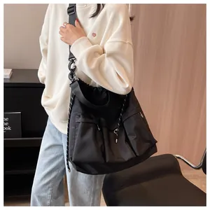Detail of black nylon crossbody bag featuring three front pockets and drawstring closure