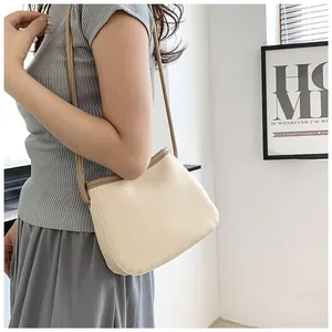Détail de sac seau crème avec texture grainée et finitions de bordure marron