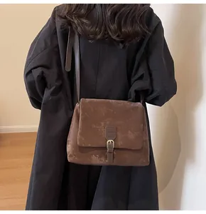 Brown retro messenger bag with buckle detail shown being worn by a model
