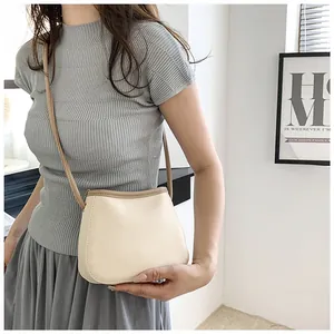 Détail du sac seau blanc cassé à texture lychee et bord marron porté par un modèle