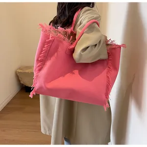 Détail du sac cabas en toile rose montrant les poignées et les bords à franges