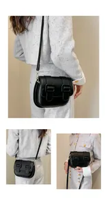 Close-up of black PU leather crossbody bag with dual decorative gold buckles and straps