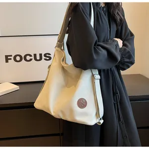 Detail of adjustable canvas strap and leather logo patch on large capacity crossbody bag