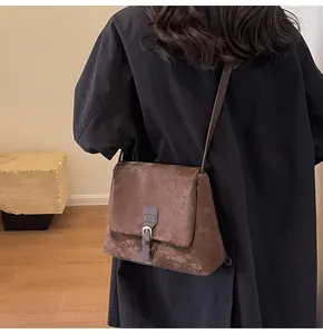 Close-up of distressed dark brown messenger bag with retro leather texture and buckle