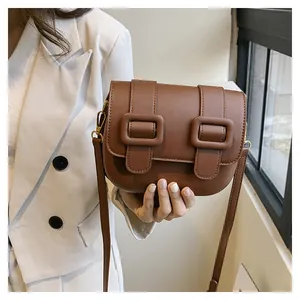 Close-up of brown vintage crossbody bag with dual buckles and golden metal hardware