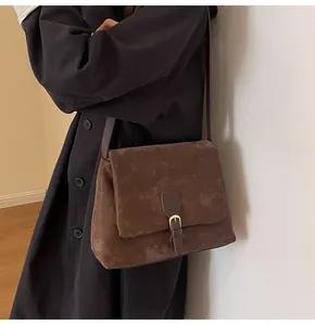 Macro shot of vintage dark brown faux leather texture and metallic buckle detail on messenger bag