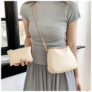Détail du sac seau beige en cuir grainé avec sa pochette assortie et sa fine bandoulière