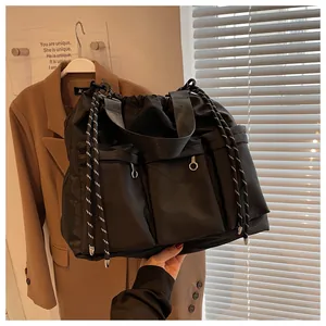 Detail of multi-pocket black nylon crossbody bag with drawstring closure and web handles