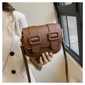 Detail view of brown vintage leather crossbody bag with dual buckles and gold hardware