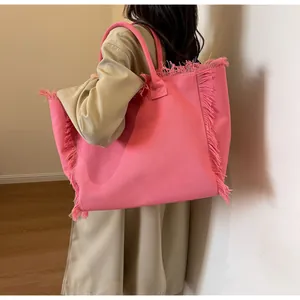 Vue latérale d'un grand sac cabas en toile rose avec franges sur un mannequin en trench