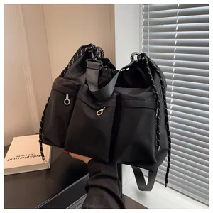 Detail of black nylon shoulder bag featuring multiple zip pockets and drawstring closure