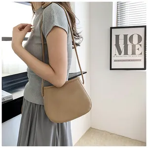 Détail de texture litchi du sac seau marron clair porté sur fond moderne minimaliste