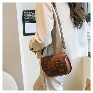 Detail view of a vintage brown crossbody bag with double square buckles on matte leather
