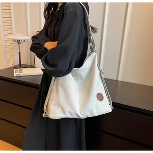 Detail of grey canvas tote bag with adjustable strap and circular leather logo patch
