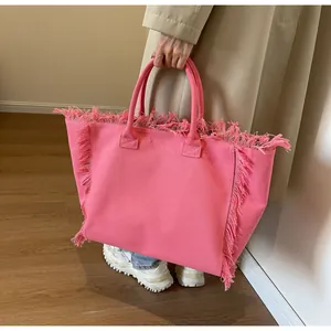 Gros plan du sac cabas en toile rose montrant les détails de franges et la texture épaisse